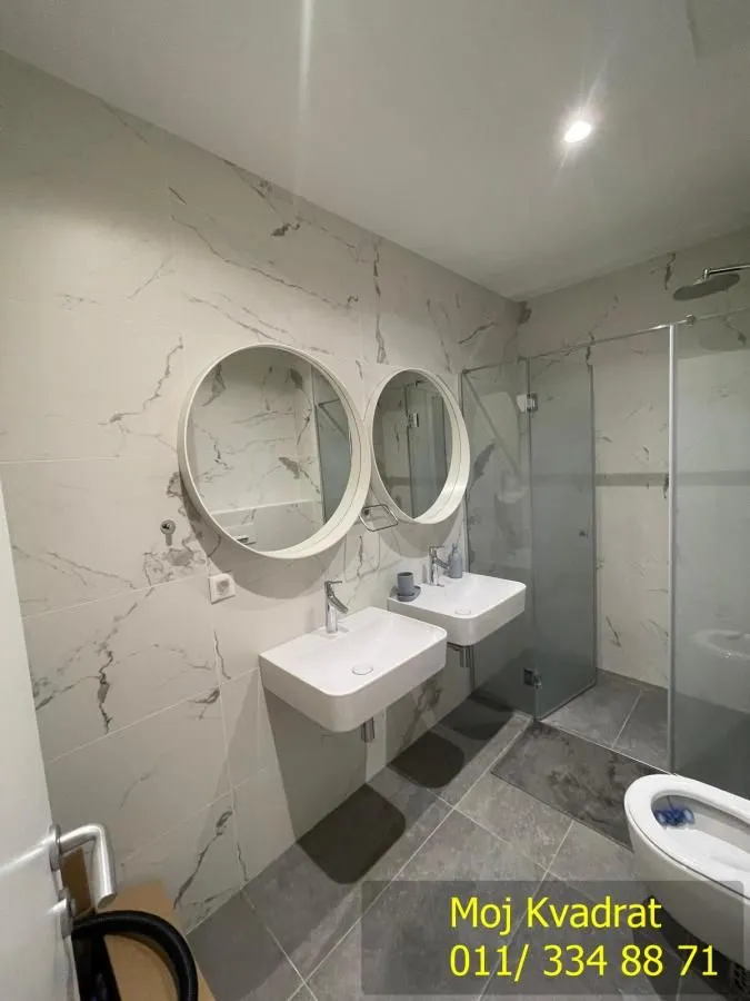 A modern bathroom equipped with two washbasins, mirrors, and a walk-in shower.