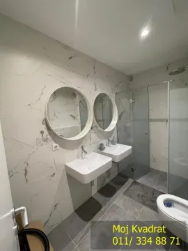 A modern bathroom equipped with two washbasins, mirrors, and a walk-in shower. - image 13