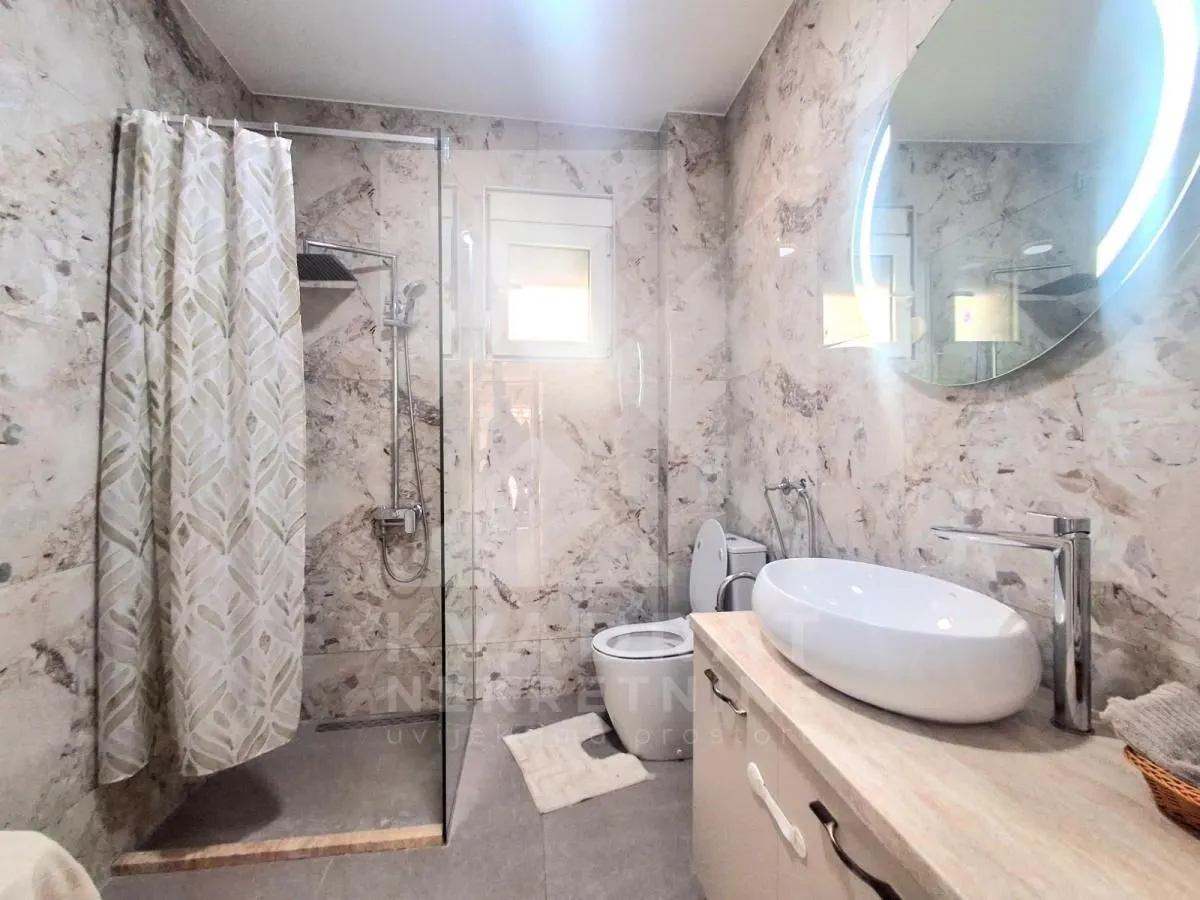Moderne kupatilo sa tuš kabinom, umivaonikom i toaletom.