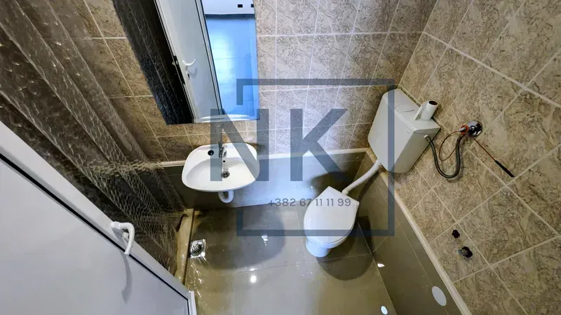 Smaller bathroom with tiling, washbasin and toilet.