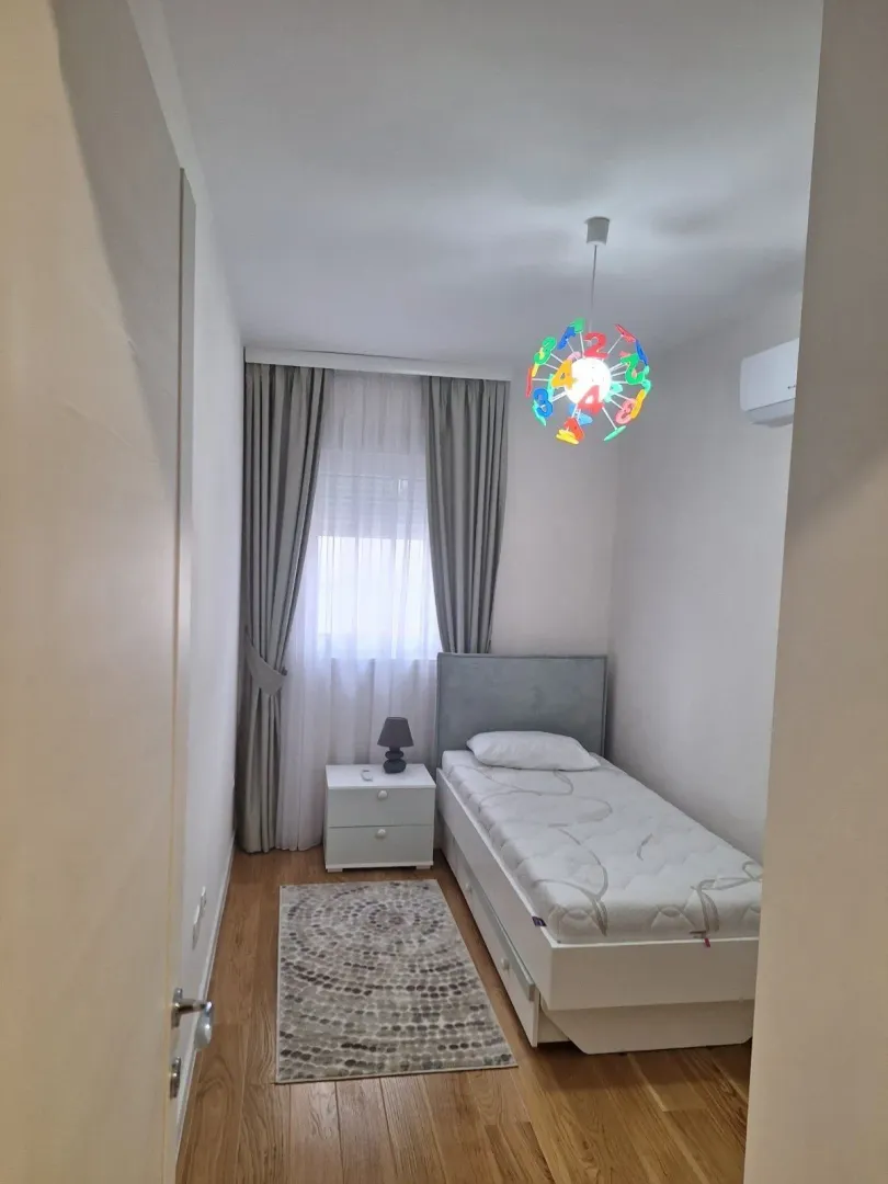 Mala spavaća soba sa jednim krevetom i šarenim lusterom.