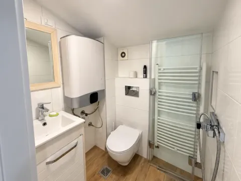 Compact bathroom with a shower cabin, washbasin, toilet, and water heater. - image 5