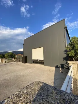 Modern grey building with a roller shutter door and paved yard. - image 4