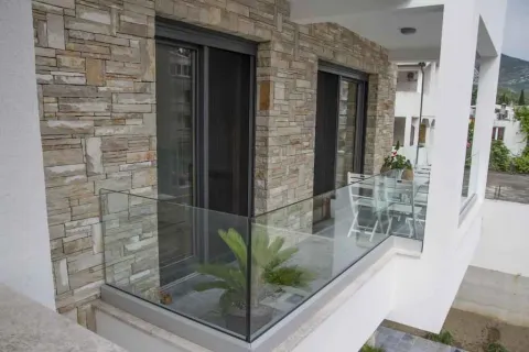 Moderan balkon sa staklenom ogradom, kamenom fasadom i garniturom za sjedjenje. - image 20
