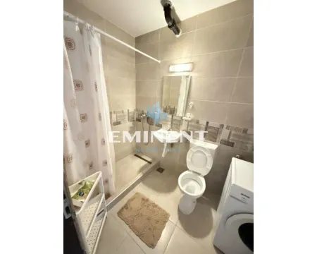 Bathroom equipped with a shower cabin, toilet, sink, and washing machine. - image 9