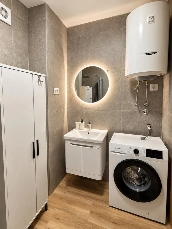 Modern bathroom with a sink, cabinet, water heater, and washing machine.