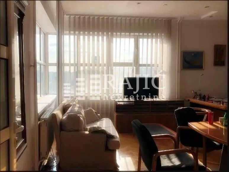 Living room with a sofa, TV, and dining area.