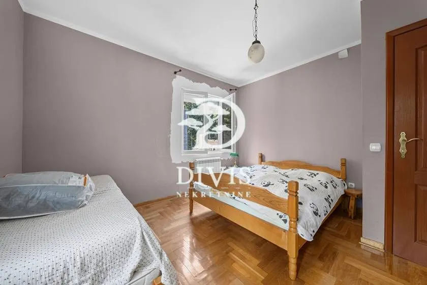 Spavaća soba sa dva kreveta i drvenim podom.