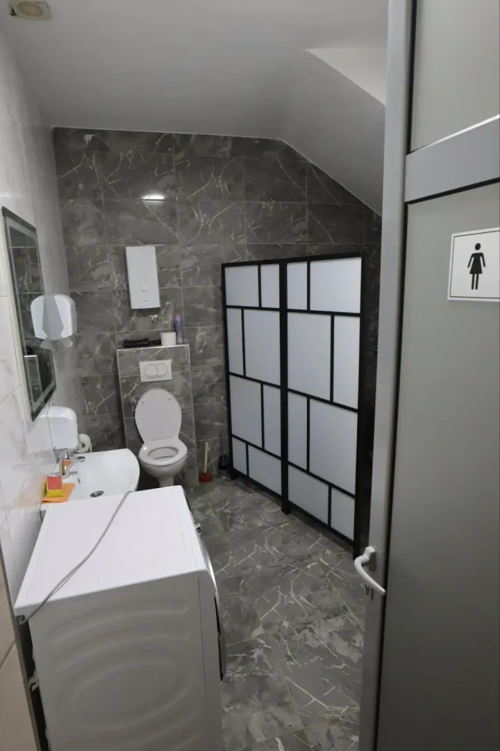 View of the bathroom with sanitary fixtures, sink, and shower cabin.