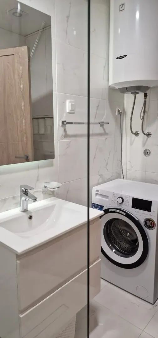 Svijetlo i moderno kupatilo sa veš mašinom i lavaboom.
