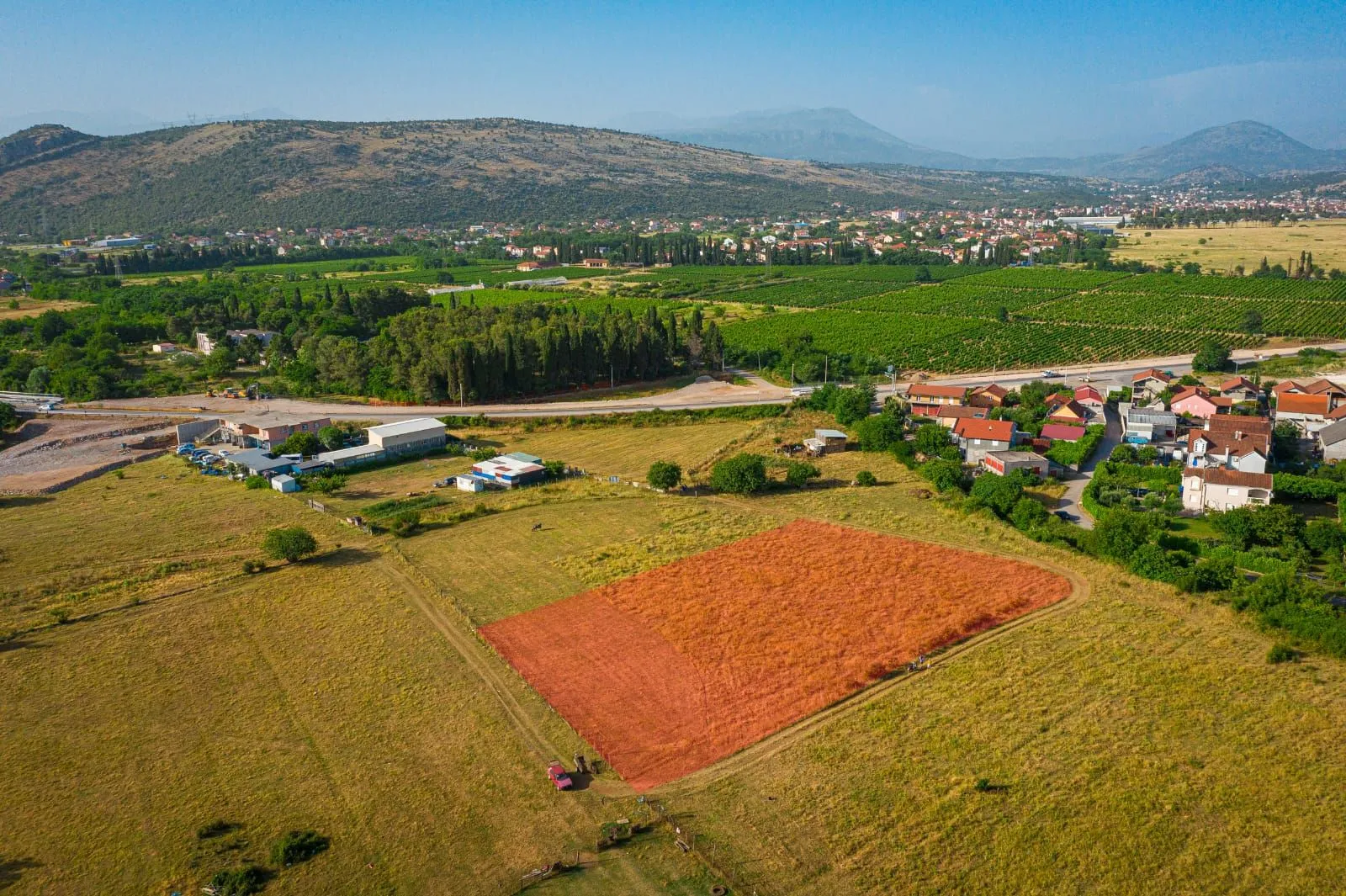 Pogled iz vazduha na zemljište sa okolnim pejzažem i naseljem u pozadini.