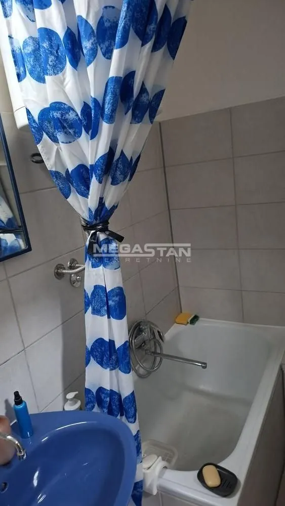 Kupatilo sa kadom i plavom zavesom za tuš.