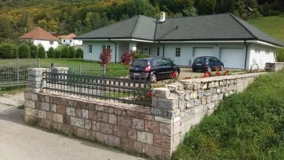 Jednospratna kuća sa prostranim dvorištem, kamenom ogradom i garažom.