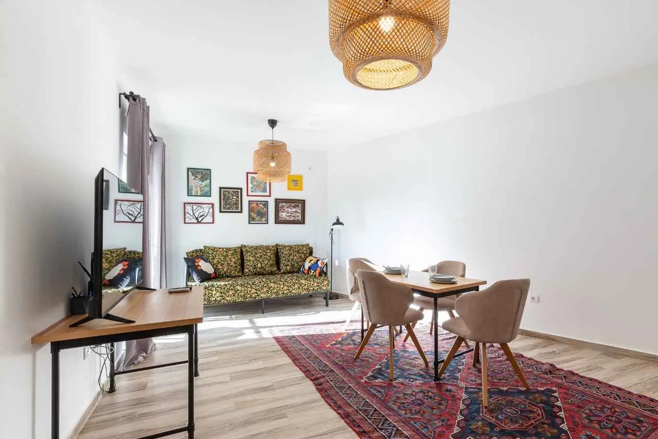 Living room with a sofa set, television, and dining table.
