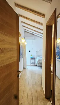 Pogled iz hodnika na uređenu spavaću sobu sa drvenim gredama na plafonu. - image 7