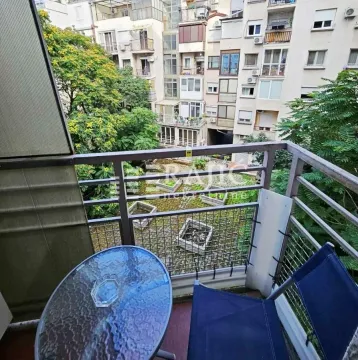 Furnished balcony with a table and chairs and a view of buildings and greenery. - image 11