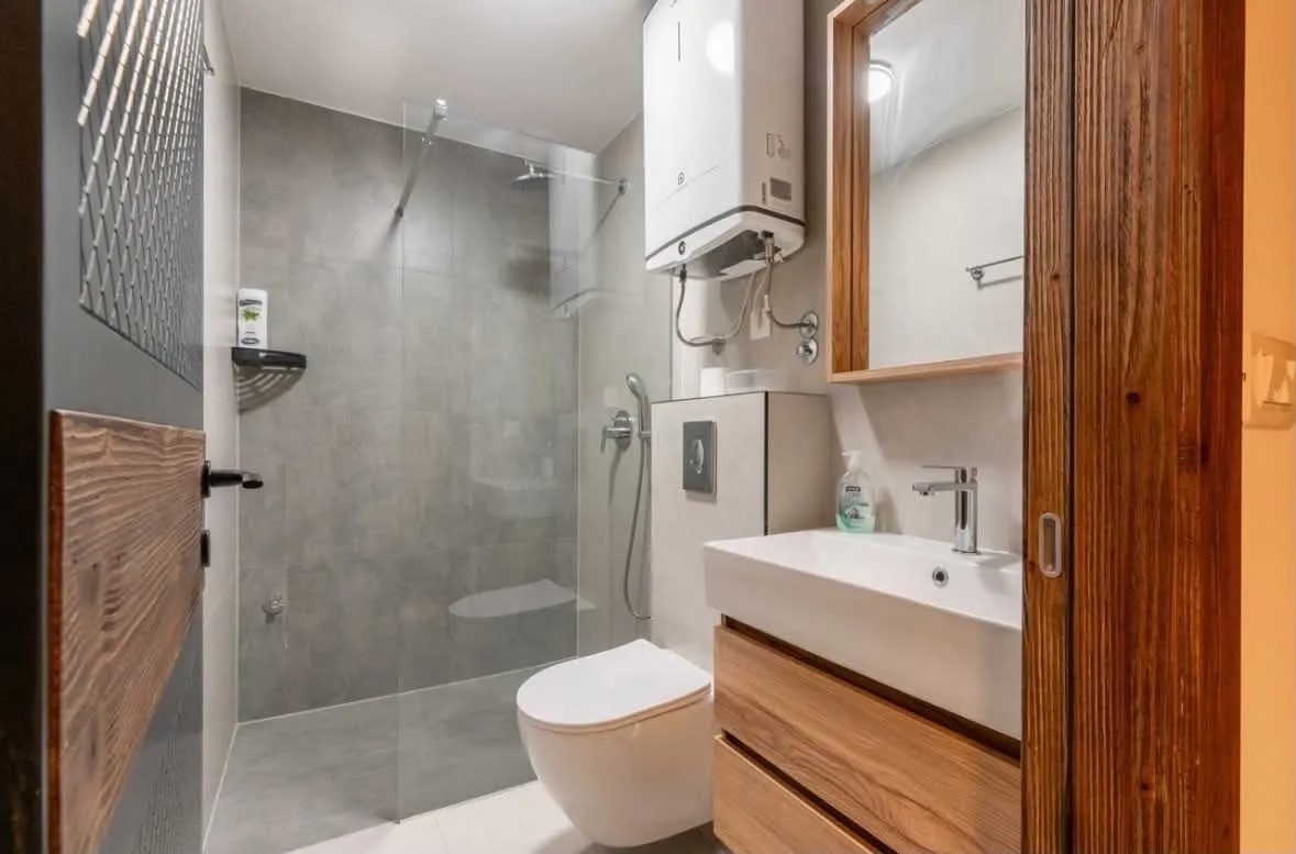 Modern bathroom with a walk-in shower, toilet, washbasin, and water heater.