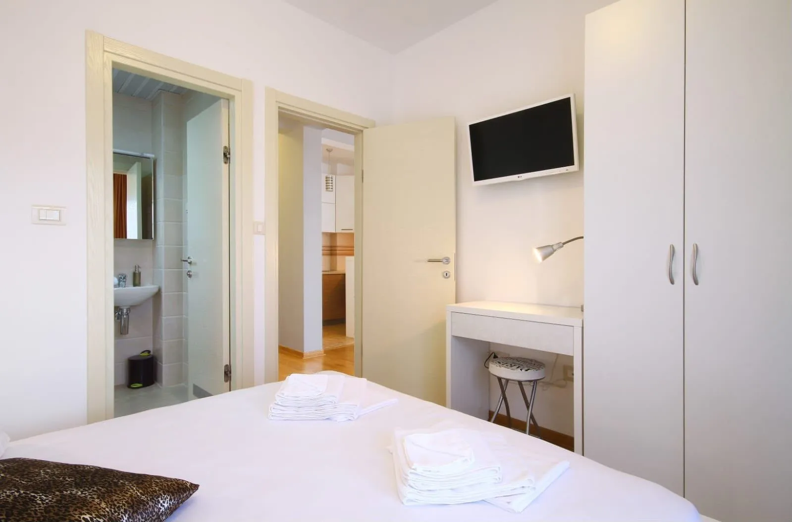 Furnished bedroom with a bed, wardrobe, desk, and view of the bathroom.