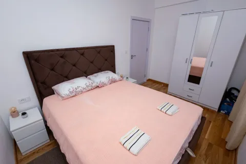 Uređena spavaća soba sa bračnim krevetom, bijelim noćnim stočićima i garderoberom. - image 2