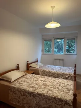 Bedroom with two wooden single beds and a window overlooking greenery. - image 12