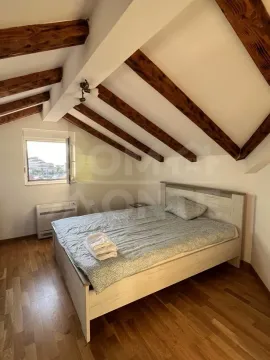 Attic bedroom with wooden beams and a double bed. - image 2