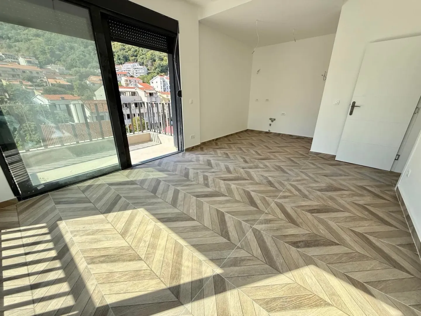 Empty room with wooden flooring and access to the terrace.