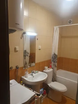 A bathroom with a bathtub, sink, and washing machine. - image 11