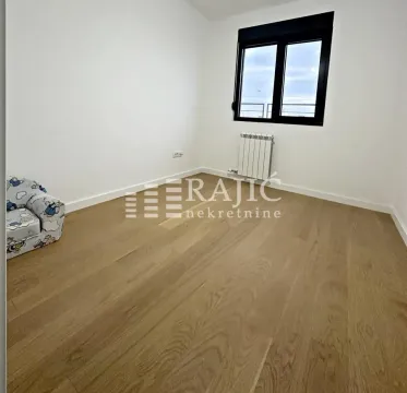 Prazna soba sa svetlim parketom, belim zidovima i prozorom. - image 9
