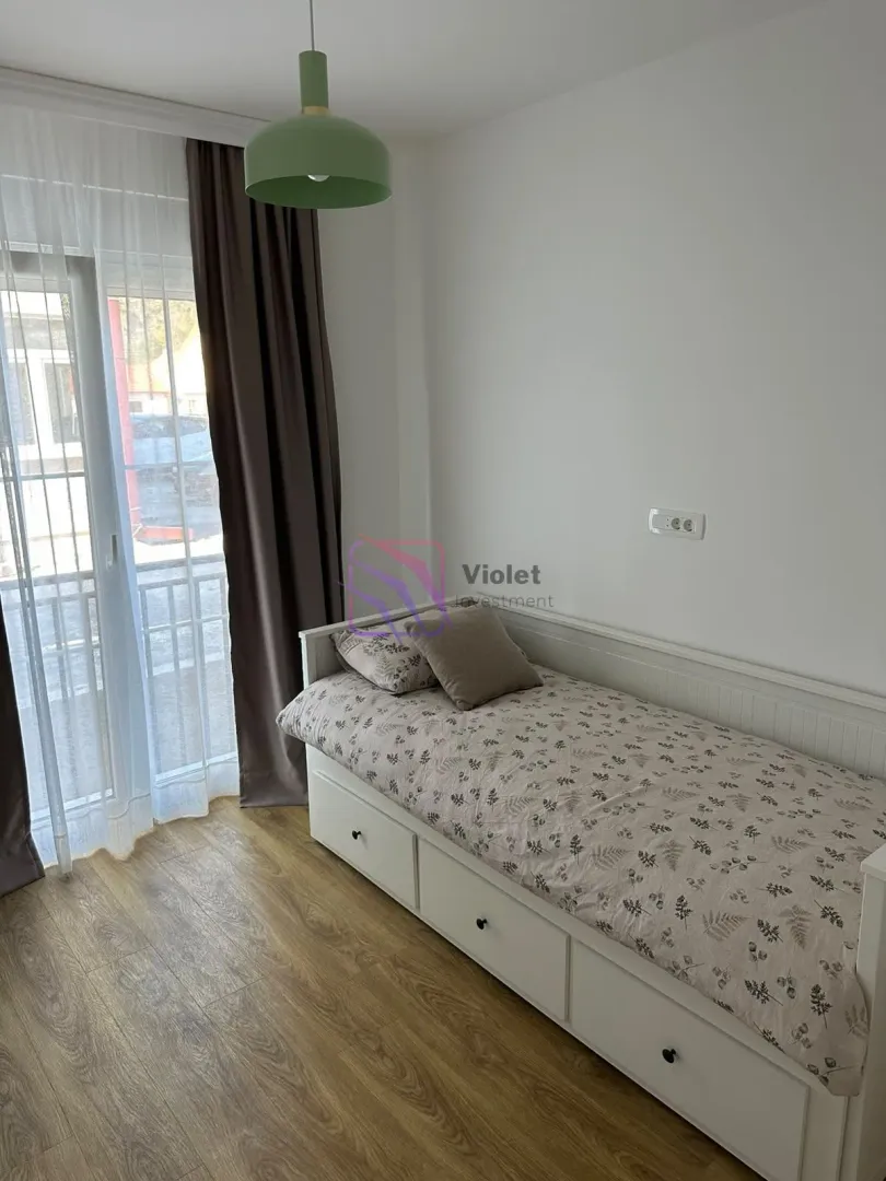 Manja spavaća soba sa krevetom na razvlačenje i izlazom na balkon.