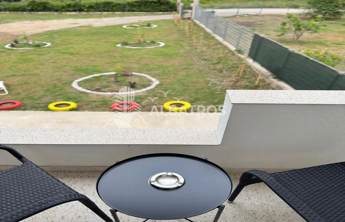 Small balcony with a black table and chairs overlooking the yard.