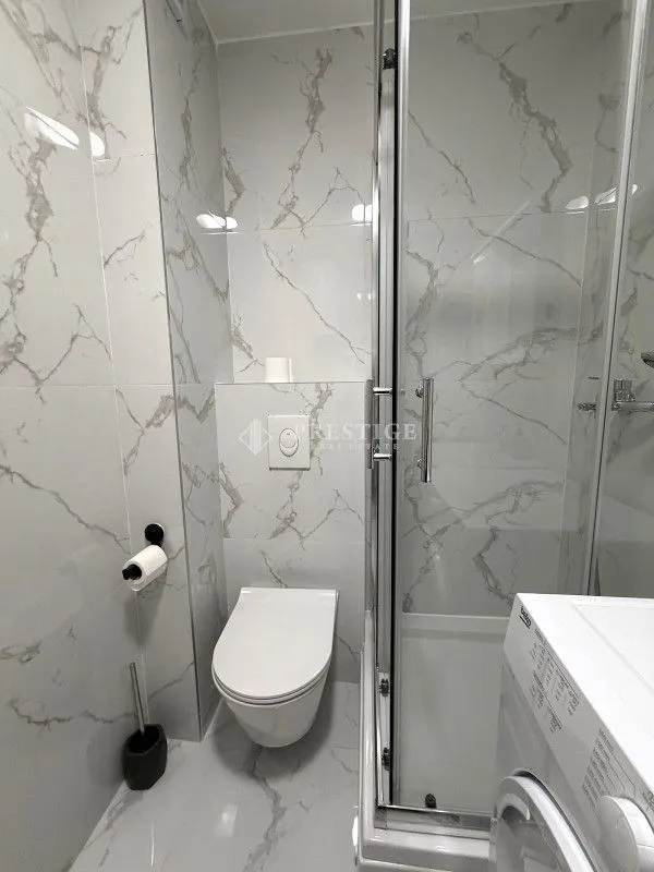 Modernly equipped bathroom with a shower cabin and marble tiles.