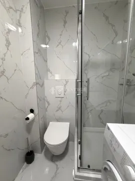 Modernly equipped bathroom with a shower cabin and marble tiles. - image 11