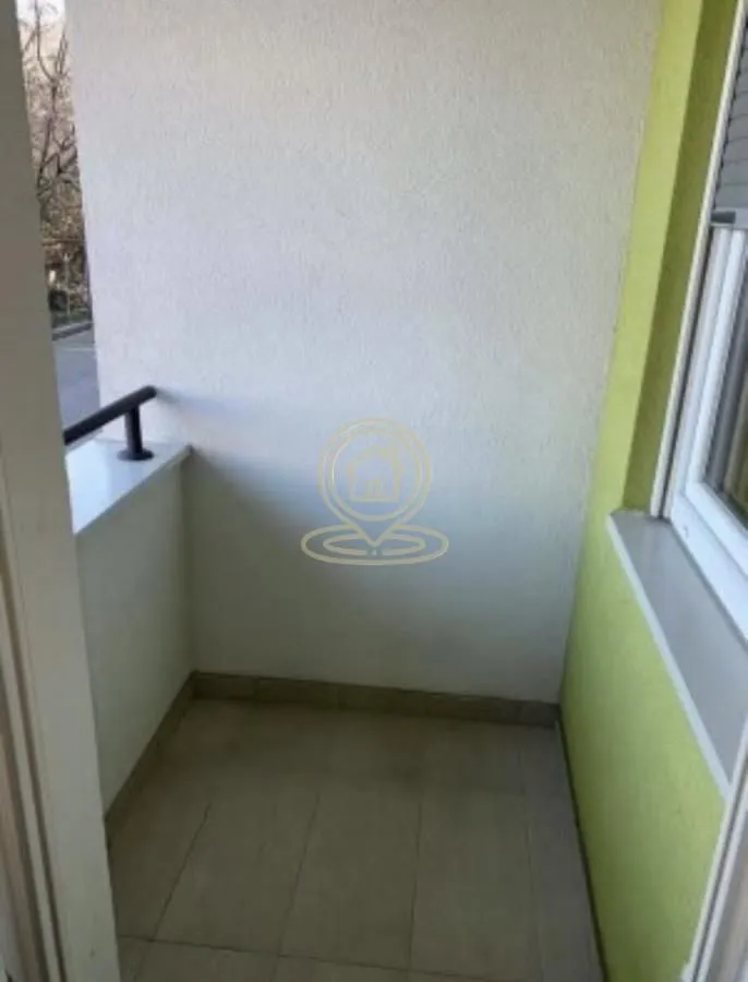 Prazan manji balkon sa keramičkim pločicama i ogradom.