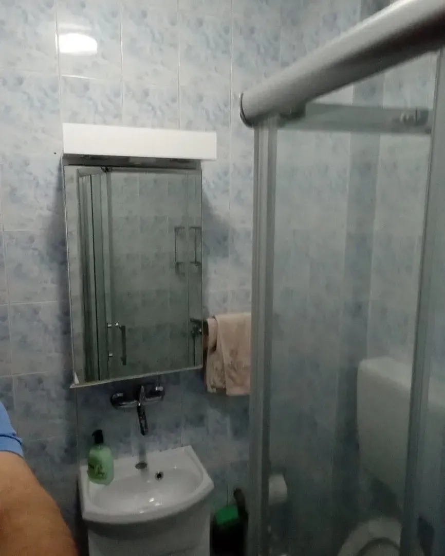 Smaller bathroom with a sink, mirror, and shower cabin.