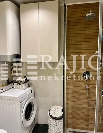 Compact bathroom with a shower cabin and a washing machine.
