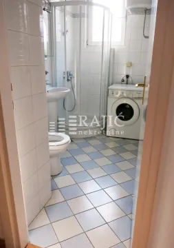 View of the bathroom with a shower cabin, washbasin, and washing machine. - image 3