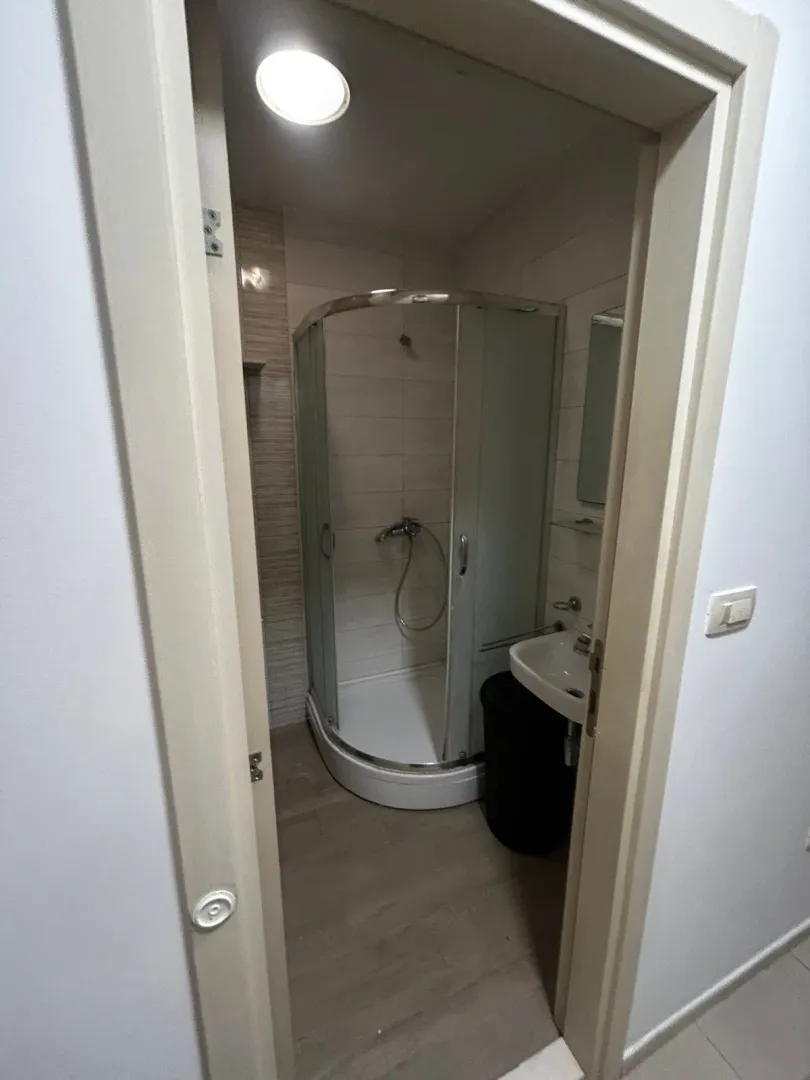 Pogled na kupatilo sa tuš kabinom kroz otvoren ulaz.