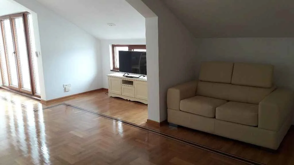 Svijetla dnevna soba u potkrovlju sa kožnom garniturom.