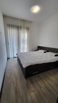 Spavaća soba sa bračnim krevetom, drvenim podom i balkonskim vratima. - image 5
