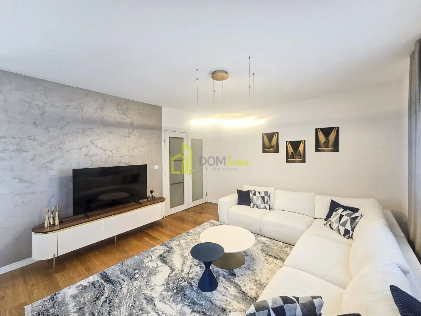 Modern living room with a sectional sofa, TV, and coffee tables.