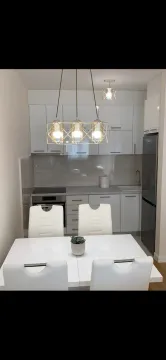 Moderna kuhinja sa trpezarijskim stolom i bijelim elementima. - image 6