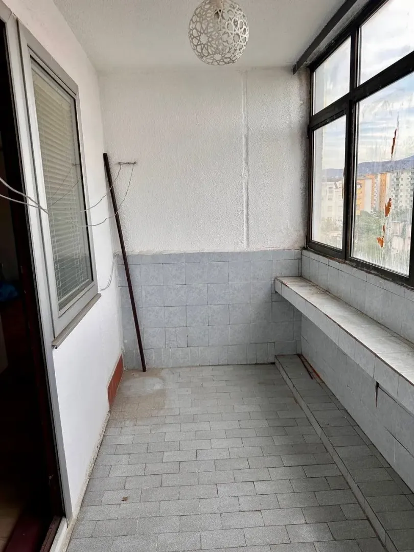 Zatvorena terasa sa pločicama na podu i zidovima i velikim prozorima.