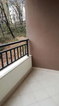 A tiled terrace with a metal railing and a view of trees. - image 9