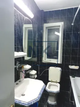Bathroom tiled in dark tiles with a washbasin, toilet and bathtub. - image 9
