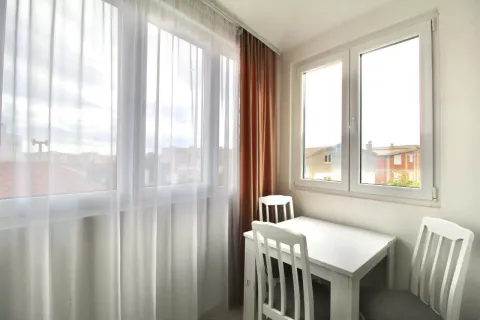 Bright dining area with a white table and chairs next to a large window. - image 5