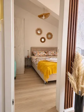 A view through the doorway into a furnished bedroom with a double bed and a yellow throw blanket. - image 4