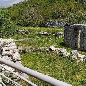 Ruined stone building in a yard overgrown with grass and vegetation. - image 3