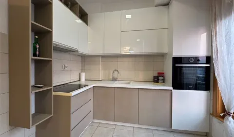 Modern kitchen with white and beige units and a built-in oven. - image 3