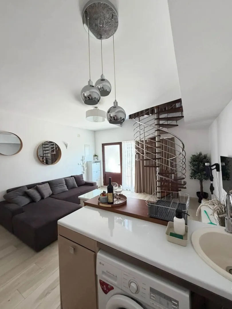 Modern living room with kitchen and spiral staircase.