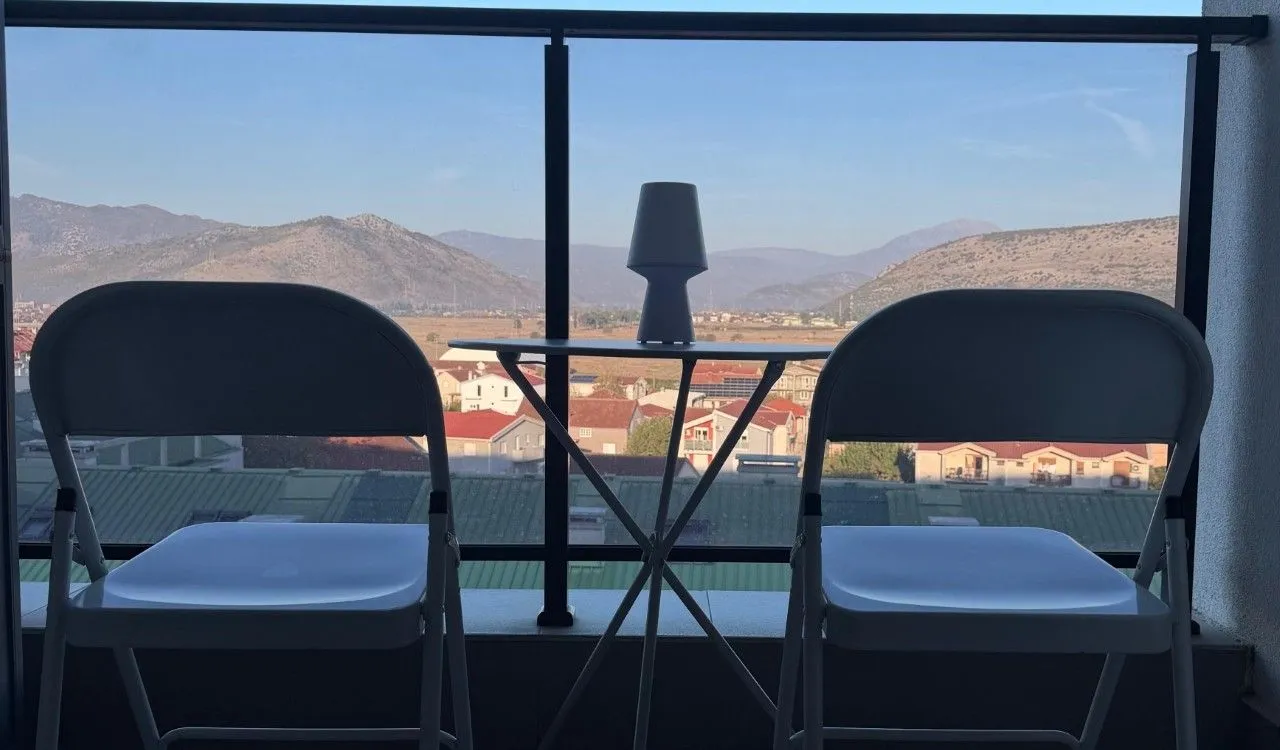Manji sto i dvije stolice na terasi sa pogledom na planine.